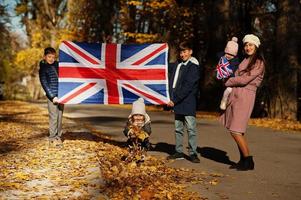 Nationalfeiertag des Vereinigten Königreichs. Familie mit britischen Flaggen im Herbstpark. Britentum feiert Großbritannien. Mutter mit vier Kindern. foto