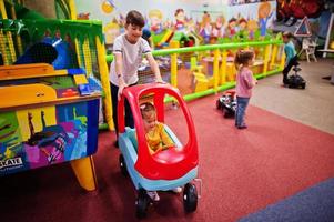Vier Kinder spielen im Indoor-Spielzentrum. Kindergarten oder Vorschulspielzimmer. Spielzeugauto fahren. foto