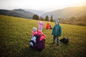 Mutter mit vier Kindern im Gras wunderschöne Bergkette am Horizont. foto