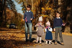 Nationalfeiertag des Vereinigten Königreichs. Vier Kinder mit britischen Flaggen im Herbstpark. Britentum feiert Großbritannien. foto