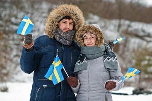 skandinavisches paar mit schwedenflagge in der schwedischen winterlandschaft. foto