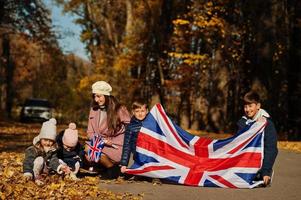 Nationalfeiertag des Vereinigten Königreichs. Familie mit britischen Flaggen im Herbstpark. Britentum feiert Großbritannien. Mutter mit vier Kindern. foto