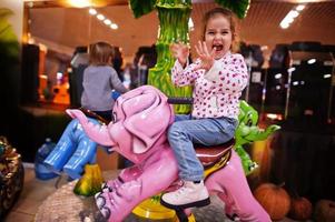 Zwei Schwestern fahren im lustigen Kinderzentrum auf einem Elefantenkarussell. foto