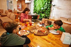 Mutter mit vier Kindern isst Pizza in Pizzeria. foto