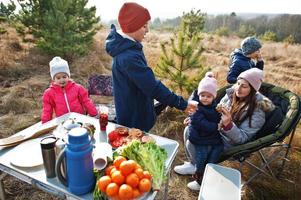 Familie beim Grillen auf einer Terrasse im Pinienwald. Grilltag mit Grill. foto