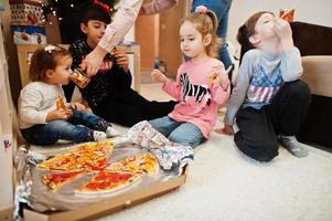 glückliche familie mit vier kindern, die zu hause pizza essen. foto