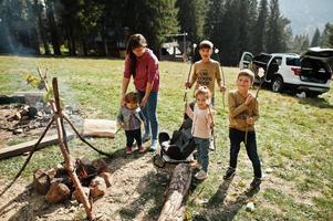 familienlagerfeuer im berg. vier kinder campen. BBQ-Marshmallow. Herbstwanderung und Lagerwetter. Erwärmen und Kochen in der Nähe einer Flamme zusammen. foto