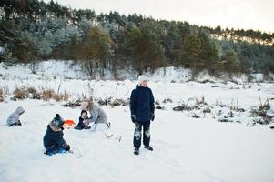 mutter, die mit kindern in der winternatur spielt. draußen im Schnee. foto