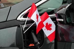 Kanada-Flagge ökologisches Autokonzept. Stromversorger einstecken, modernes Auto aufladen. foto