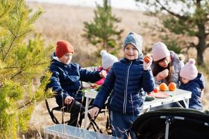 Fröhliche Mutter mit Kindern bei einem Picknick. Familie im Urlaub mit Früchten im Freien. foto