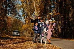 Nationalfeiertag des Vereinigten Königreichs. große familie mit vier kindern, die britische fahnen im herbstpark halten. Britentum feiert Großbritannien. foto