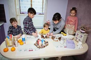 mutter mit vier kindern macht einen kranz für heiligabend und bastelt dekorieren. Neujahr Feierlichkeiten. foto