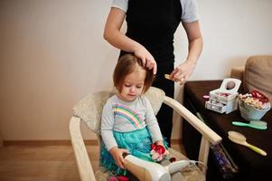 mutter und tochter wochenende zusammen zu hause, mutter macht frisur für babymädchen. foto