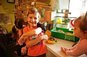 kinder, die ihre lieblingshaustiere an den händen halten. Kinder spielen zu Hause mit Hamster, Schildkröte und Papageien. foto