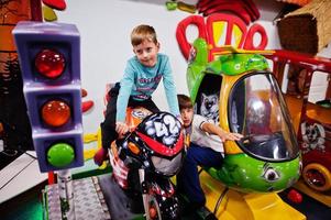 zwei brüder sitzen auf motorrad- und hubschrauberattraktion auf dem spielplatz. foto