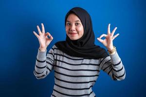 porträt der glücklich lächelnden asiatischen muslimfrau zeigt ok fingerzeichengeste foto