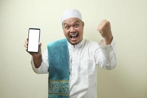 Fette asiatische muslimische Männer sehen überrascht aus über die guten Nachrichten am Telefon foto