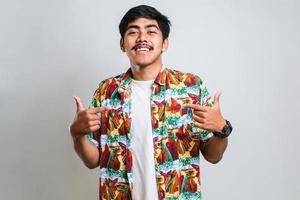 asiatischer mann mit lässigem hemd, der selbstbewusst mit einem lächeln im gesicht aussieht und sich mit den fingern zeigt foto