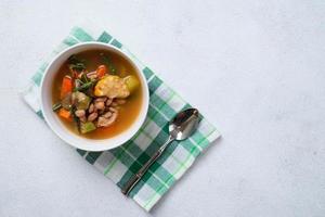 sayur asam hautnah in weißer schüssel über holztischhintergrund foto