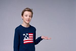 junger patriotischer Teenager mit blauem Pullover mit Flagge der Vereinigten Staaten von Amerika foto