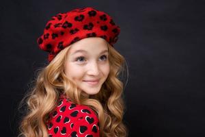 französische Modeikone. glückliches Kind mit französischer roter Baskenmütze und Kleid auf Schwarz foto