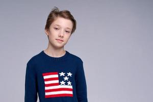 junger patriotischer Teenager mit blauem Pullover mit Flagge der Vereinigten Staaten von Amerika foto