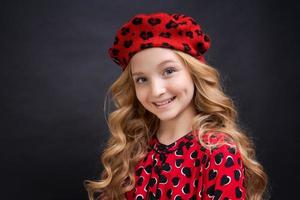 französische Modeikone. glückliches Kind mit französischer roter Baskenmütze und Kleid auf Schwarz foto