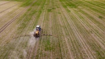 Luftbild von landwirtschaftlichen Traktoren, die auf dem Feld pflügen und sprühen foto