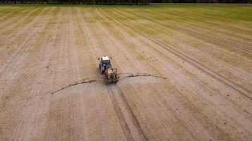 Luftbild von landwirtschaftlichen Traktoren, die auf dem Feld pflügen und sprühen foto