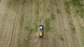 Luftbild von landwirtschaftlichen Traktoren, die auf dem Feld pflügen und sprühen foto