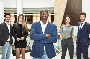 fröhlicher junger afrikanischer Mann in der Abendgarderobe, die Arme verschränkt hält foto