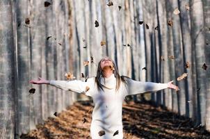 Schönes blondes Mädchen mit fallenden Blättern im Herbstpark foto