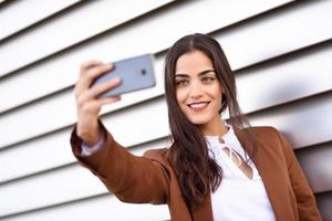 junge frau, die selfie-foto mit smartphone im städtischen hintergrund macht foto