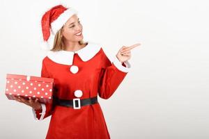 blonde frau in weihnachtsmannkleidung, die mit geschenkbox lächelt. foto