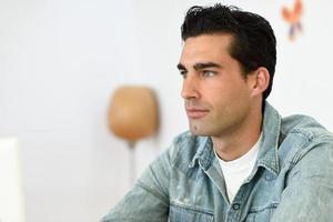 Gut aussehender Mann mit Jeanshemd, der in einer Kaffeebar sitzt foto