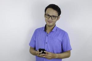 lächeln und glückliches gesicht des jungen asiatischen mannes mit telefon in der hand. Werbemodellkonzept mit blauem Hemd. foto
