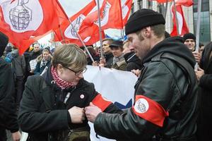 Moskau, Russland - 10. März 2019. Politische Kundgebung für ein kostenloses Internet. Nationalbolschewik bindet eine rote Armbinde mit dem Emblem der Partei am Arm des Mädchens foto