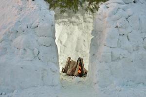 Lagerfeuer, das gerade in einem Schneehaus-Iglu angezündet wurde, das gerade aus Schneeziegeln gebaut wurde foto