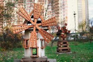 Modell einer alten hölzernen Windmühle auf einem Kinderspielplatz mit Haus im Hintergrund foto