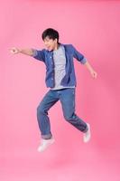 junger asiatischer mann, der auf blauen hintergrund springt foto