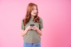 junge asiatische Frau mit Smartphone auf rosa Hintergrund foto