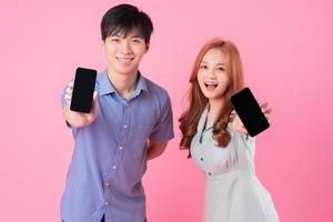 junges asiatisches Paar mit Smartphone auf rosa Hintergrund foto