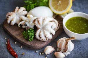 Tintenfischsalat Gewürze Zitronen-Knoblauch-Chili-Sauce auf Holzschneidebrett Hintergrund - gekochte Tintenfische Tintenfische oder Tintenfische im Fischrestaurant foto