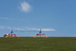 der blaue himmel und die weißen wolken neben dem qinghai-see sowie einige zelte und gebetsfahnen auf dem grasland foto