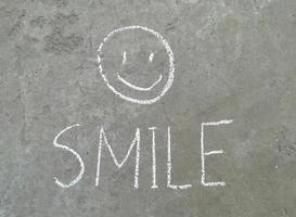 Lächeln ist mit Kreide auf den Asphalt gezeichnet. kinderkreativität, sommer, freude, gefühl, glück foto