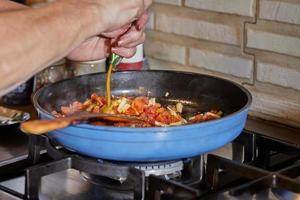 Tomatensauce, Pilze und Kapern werden in der Pfanne auf dem Gasherd zum Kochen der Kalbszunge gebraten. französische Gourmetküche foto