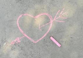 Rosa Herz und Pfeil mit Kreide auf den Asphalt gezeichnet. Liebeserklärung. bannerplatz für text, valentinstag, kinderkreativitätskopierraum, sommer foto