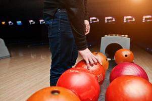 Nahaufnahme der Hand des Bowlingspielers, die den roten Ball aus dem Schüssellift nimmt foto