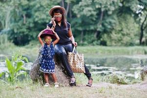 stilvolle afroamerikanische mutter und tochter bei sonnenbrillen. schwarze Frau mit Handy foto