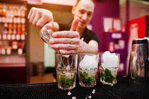 Barkeeper bereitet Mojito-Cocktailgetränk an der Bar zu foto